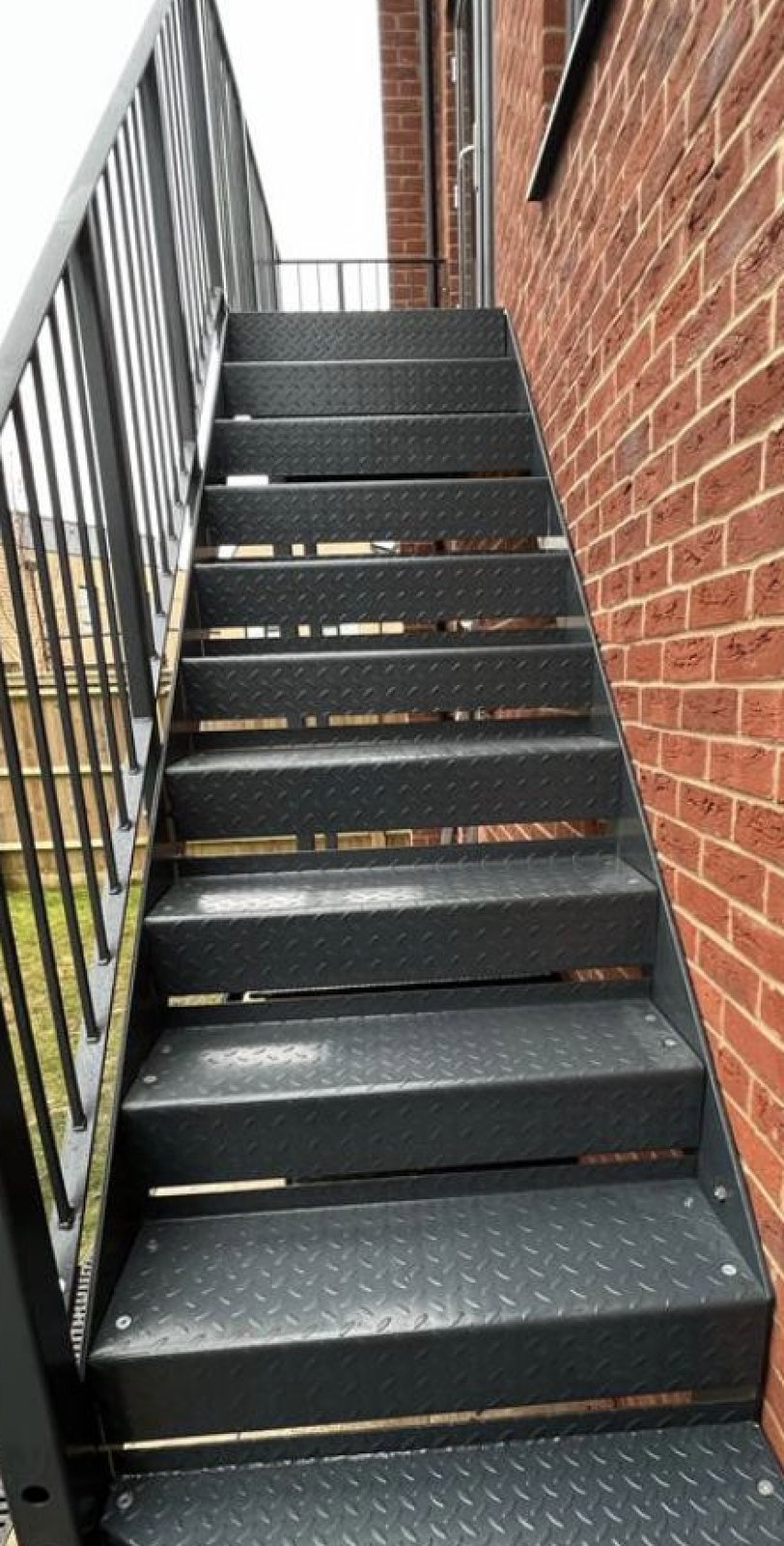 Side of a red brick building: outdoor flight in black, durbar treads, bar guarding