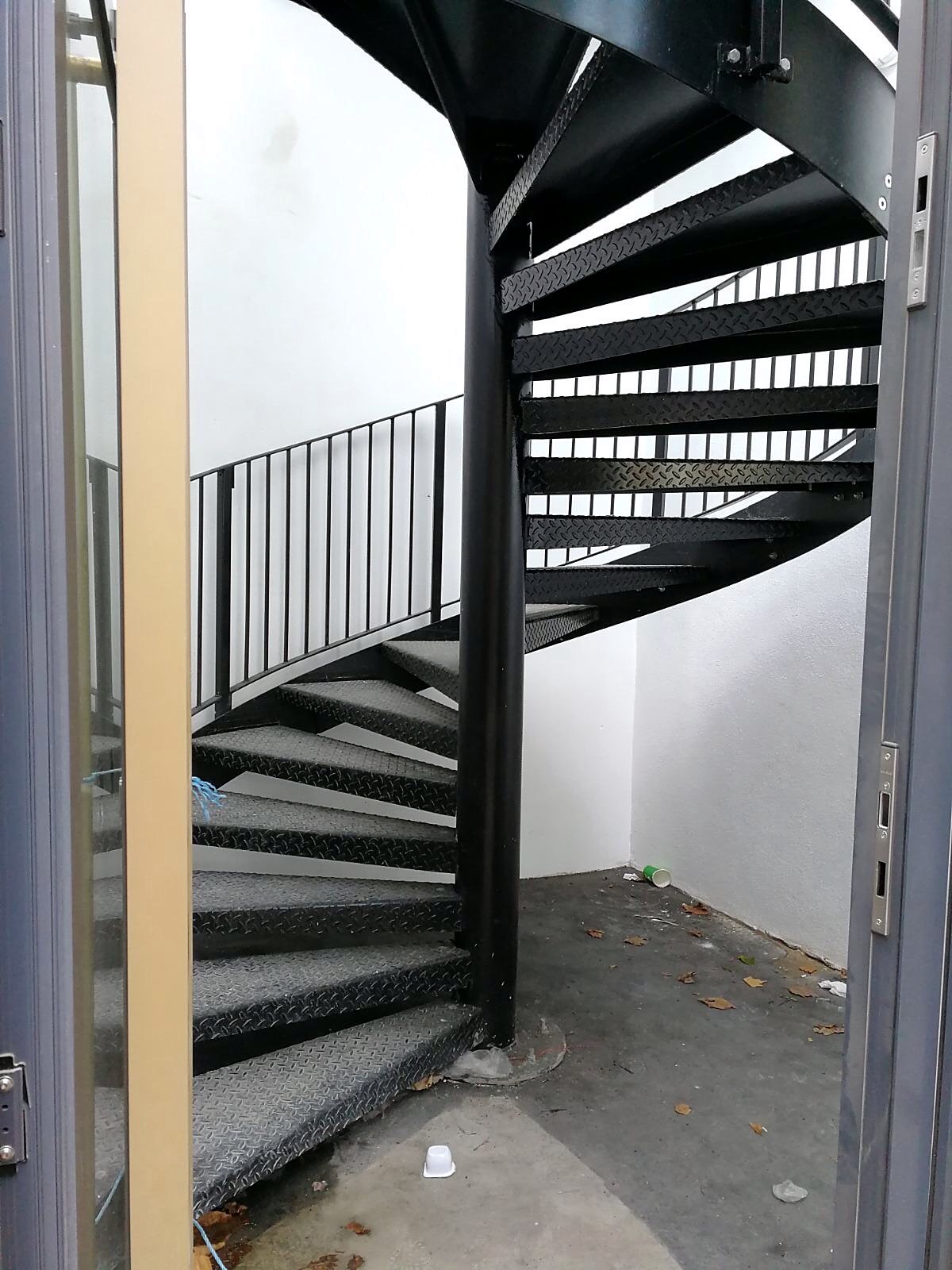 Black spiral on durbar treads corkscrewing up out of a white-walled lightwell