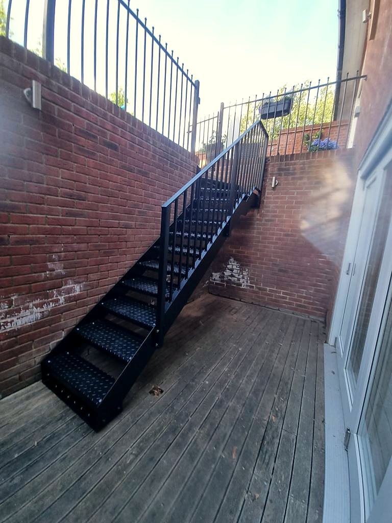 Black flight on durbar steps climbing between two brick walls up to a raised terrace