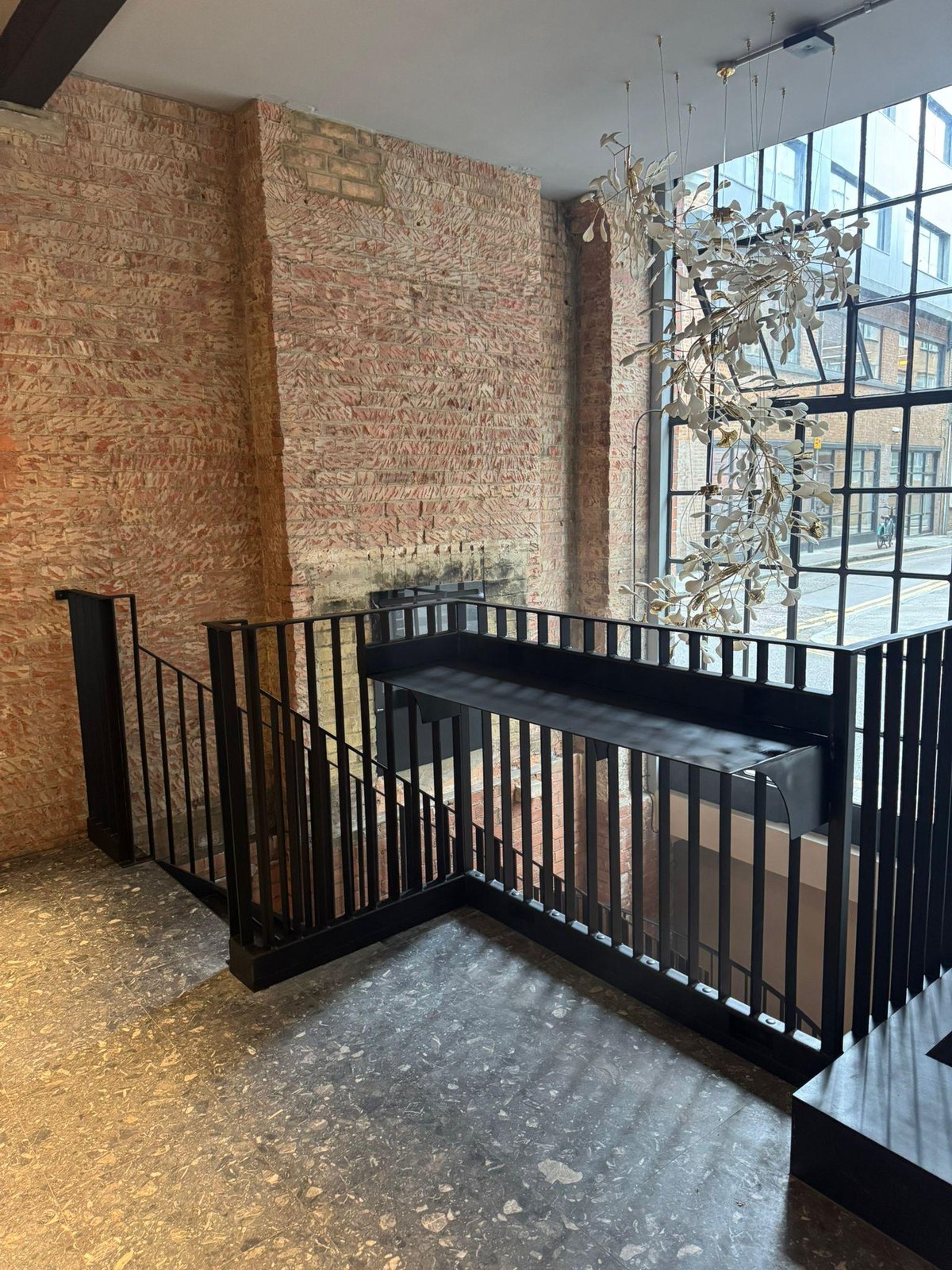 Bare brick interior: stairwell edged in black upright-bar guarding