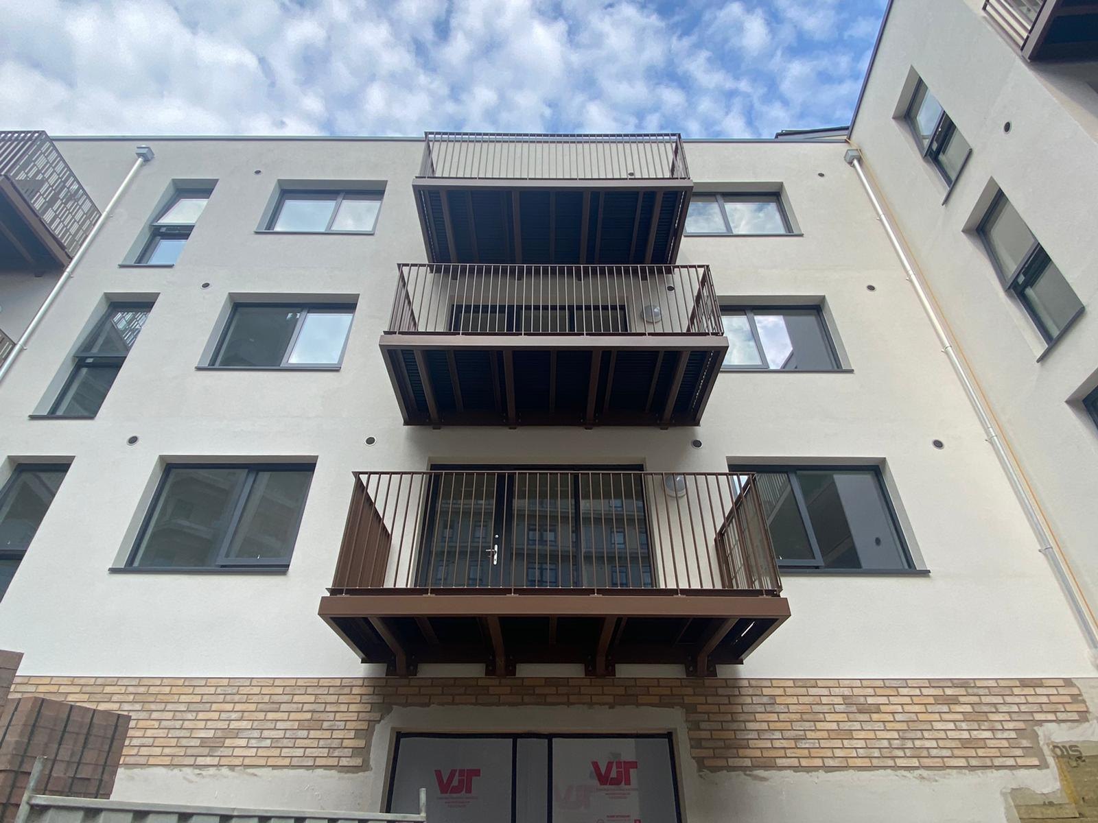 White rendered flats: stacked balconies in brown with upright bar fronts