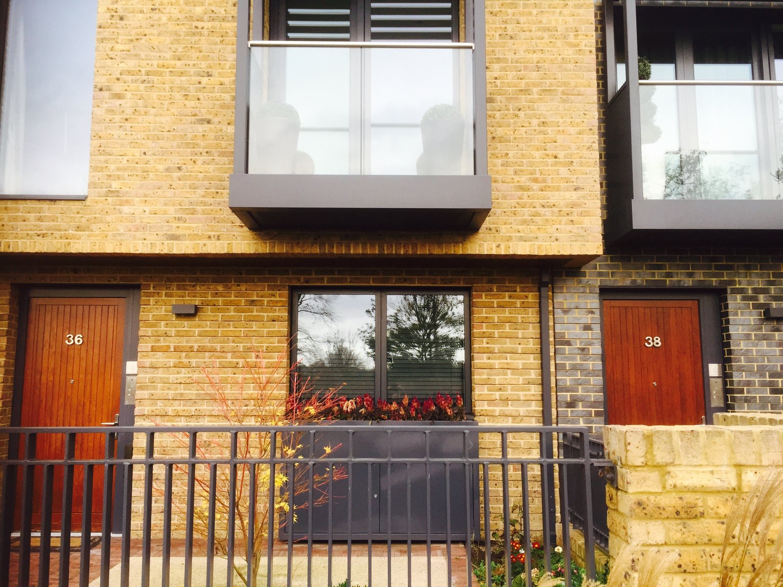 Terrace of new houses: anthracite front railings below, glass Juliets above