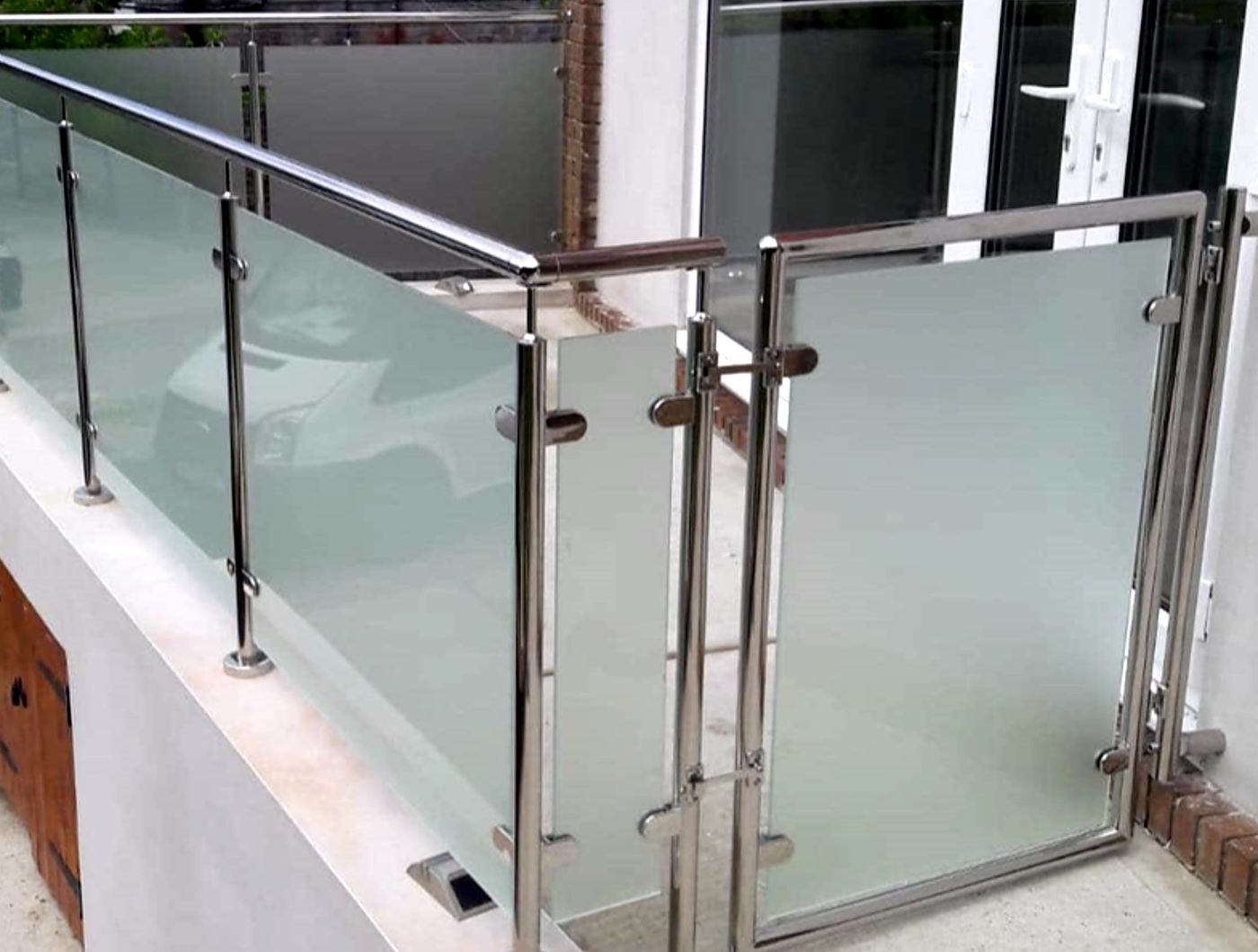 Rendered terrace with frosted panes clamped between round stainless posts and a matching gate