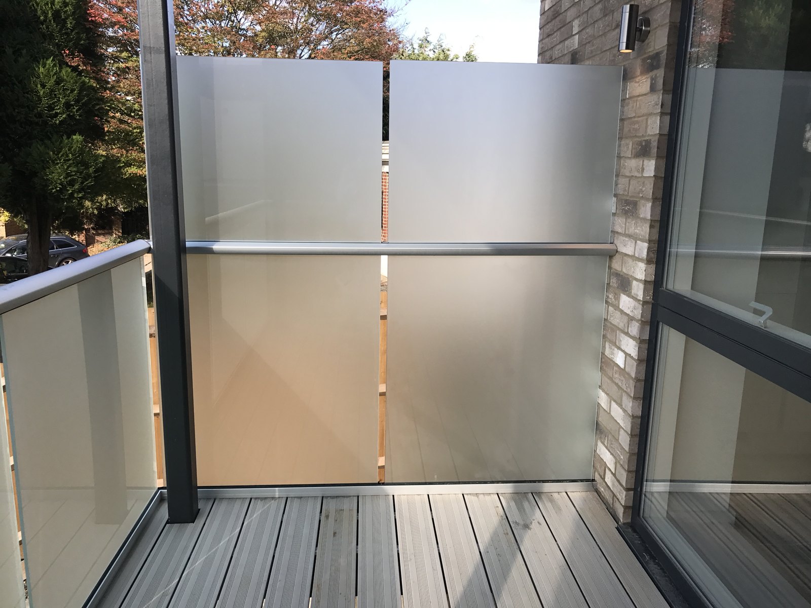 Balcony corner: obscured glass side screen meeting a clear glass front, grey top rail