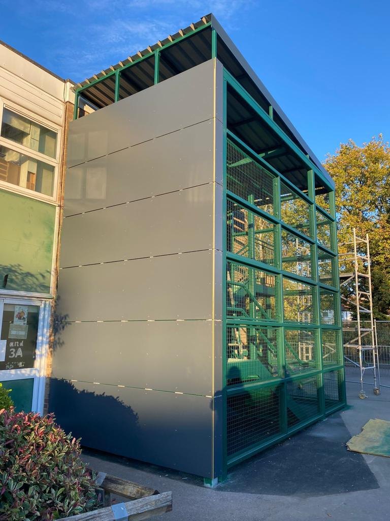 School building: escape stair tower in green steel, meshed and part clad