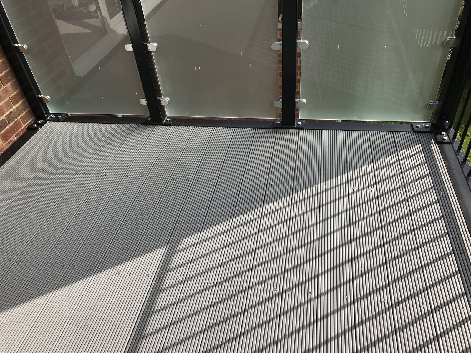 Balcony floor close up: composite boards, black uprights, obscured glass