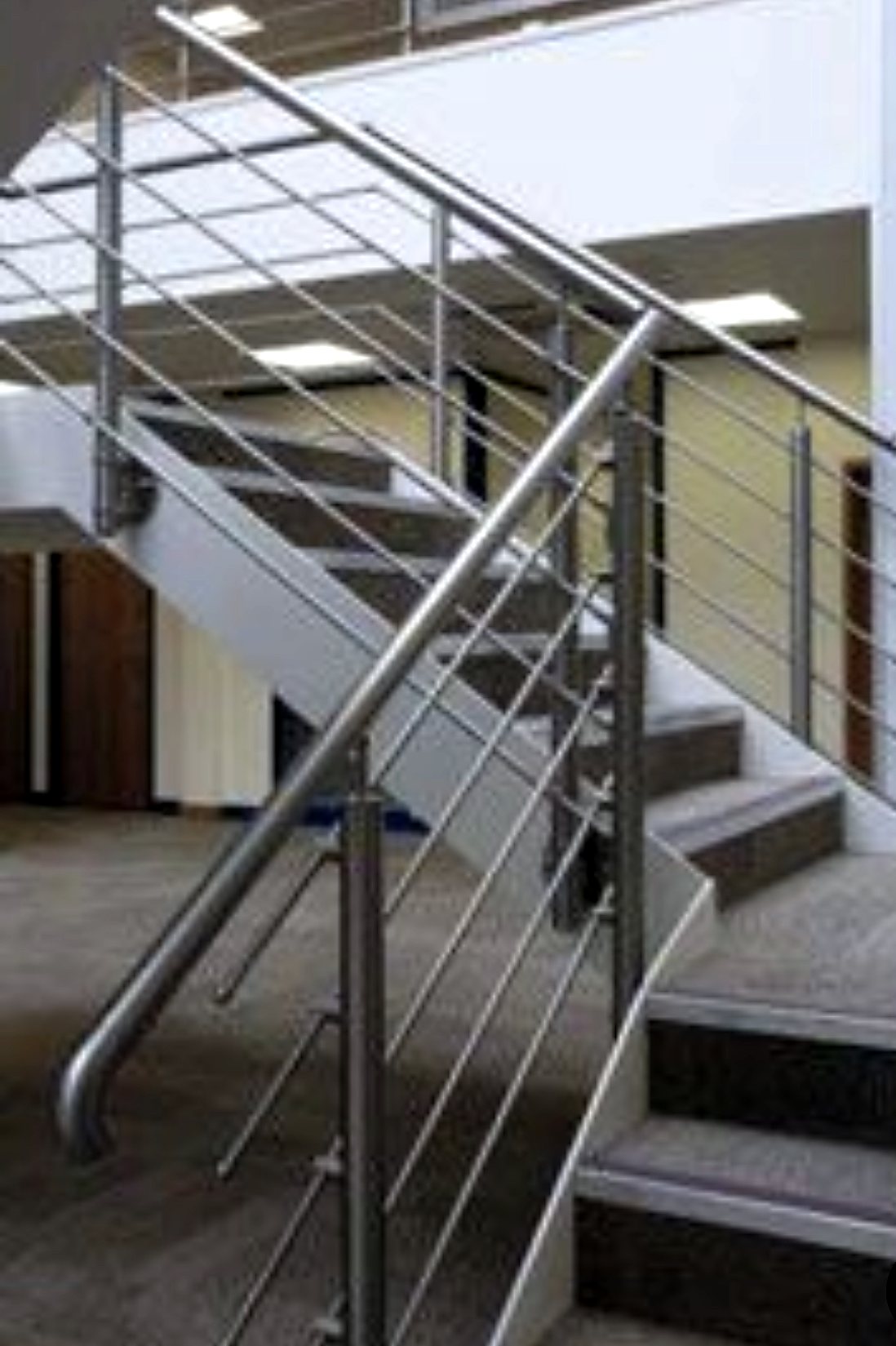 Concrete stair with satin steel guarding, horizontal rail infill and a round handrail
